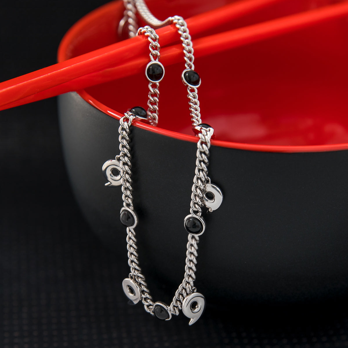 Close-up view of the adjustable curb chain and magatama charms